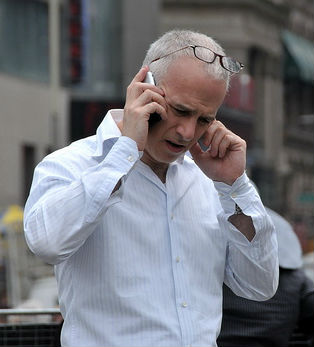 Older gentleman using cell phone on street. 