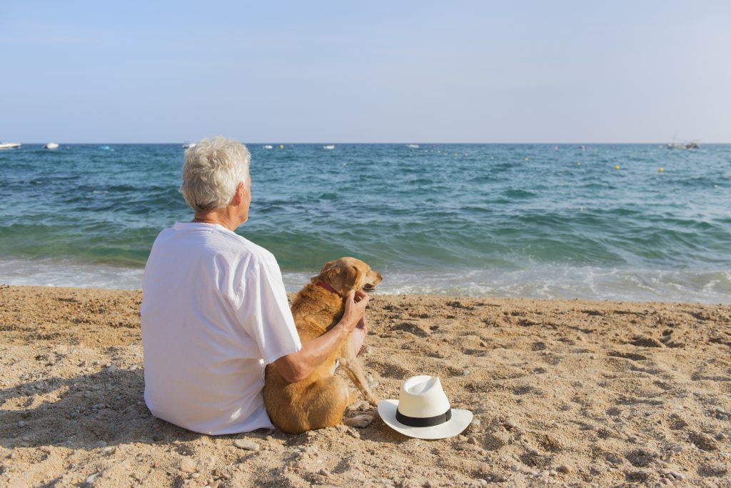Senior man with dog at the beach in California.