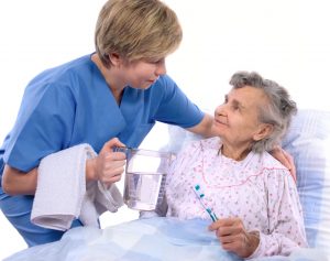 An in home caregiver comforts an elderly patient.
