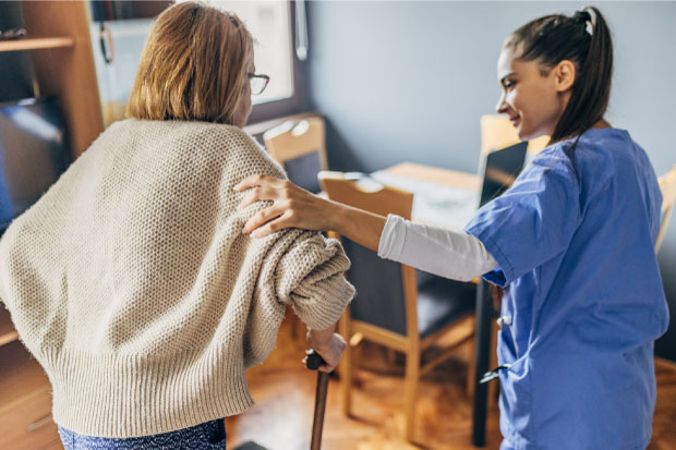 A nurse helps a senior woman to walk