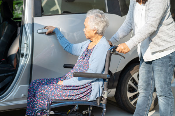 Caregiver help and support asian elderly woman sitting on wheelchair prepare get to her car to travel in holiday