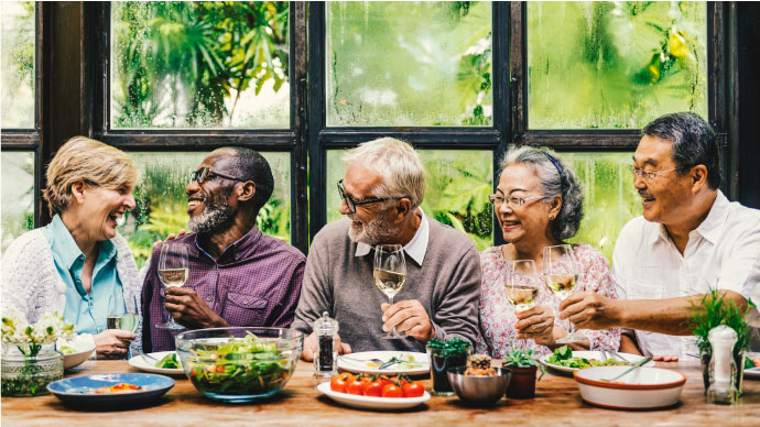 Elderly friends having a meal together smiling and laughing