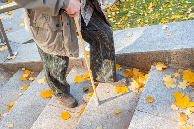 Elderly man climbs the marble stairs, city park in the fall