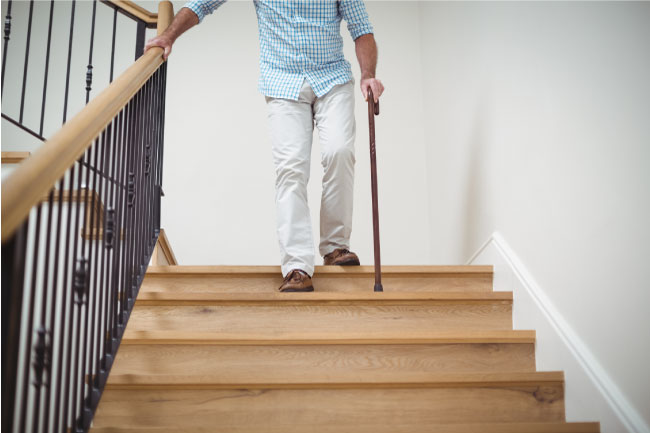 Elderly ma walking downstairs with a cane