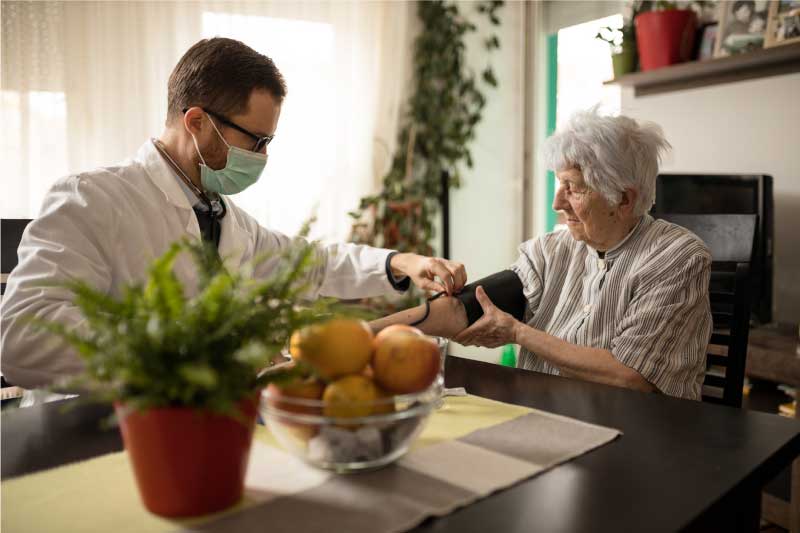 male doctor taking elderly woman's blood pressure