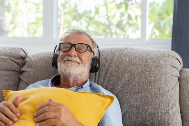 Senior retirement man listen to music using headphone feeling happy in his home