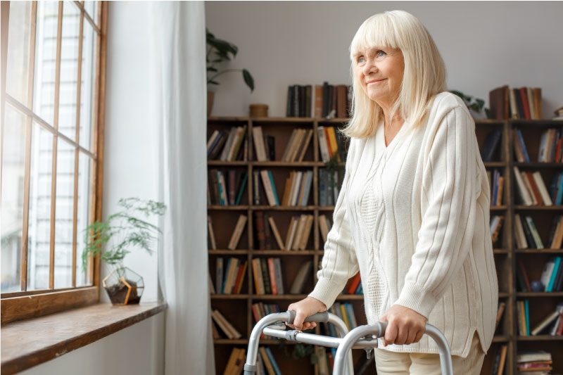 woman standing with walker smiling and looking out of the window