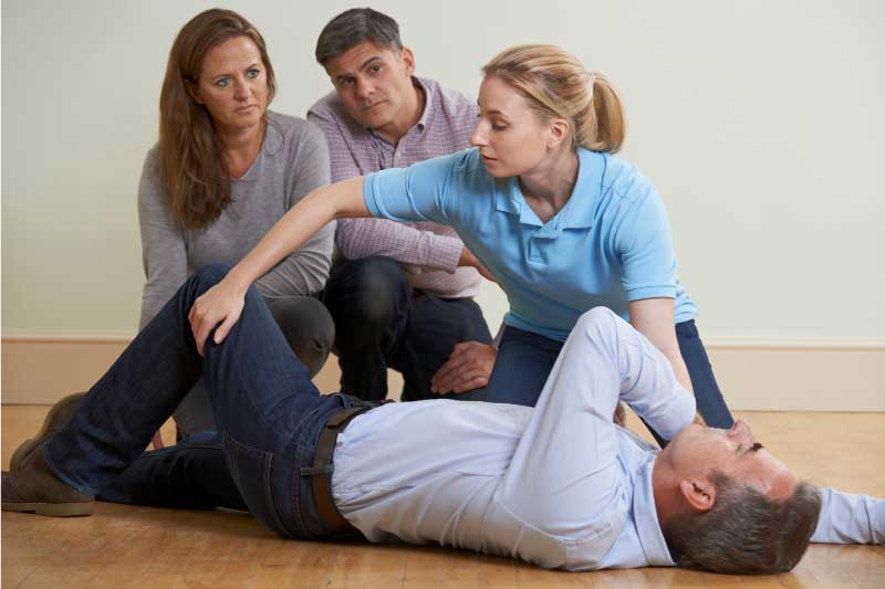 Woman-Demonstrating-Recovery-Position-In-First-Aid-Training-Class
