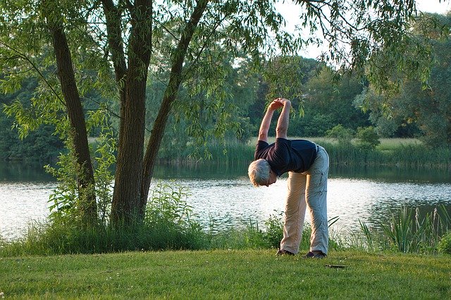 elderly man stretching outside by the lake