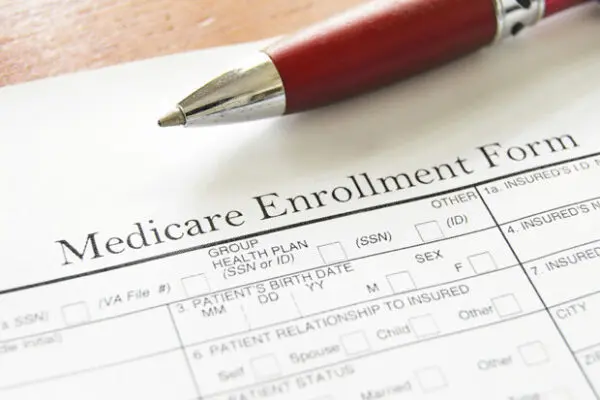 Medicare enrollment form with a pen resting on top, symbolizing senior care planning and Bay Alarm Medical medical alert support for nursing home coverage