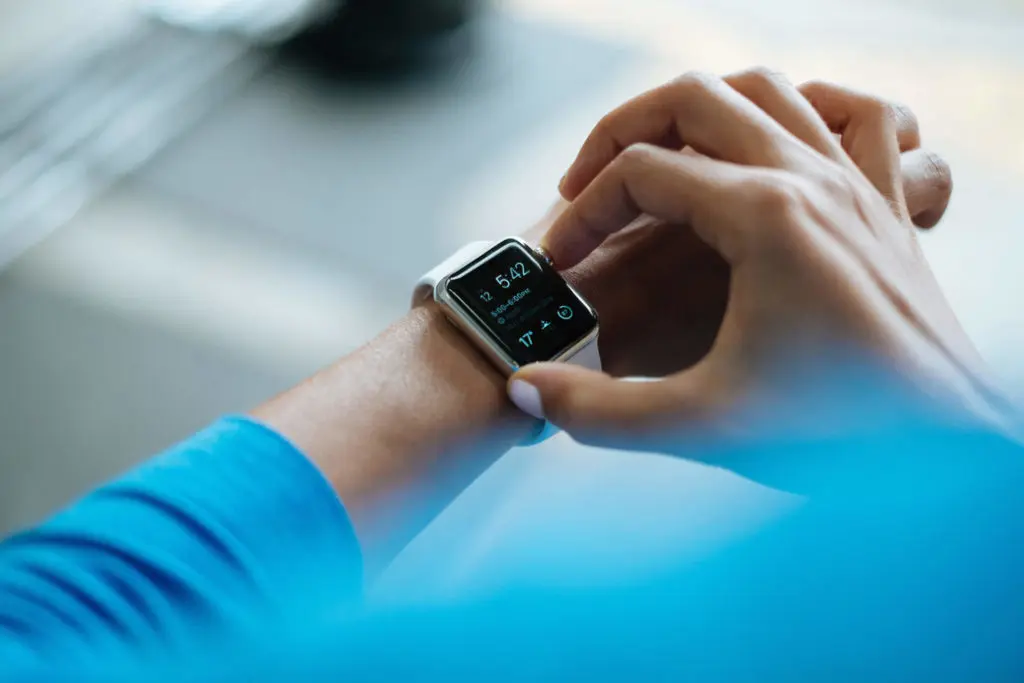 Person adjusting smartwatch with medical alert and fitness tracking features.