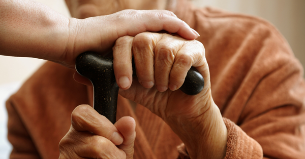 hand holding elderly person's hand holding a cane